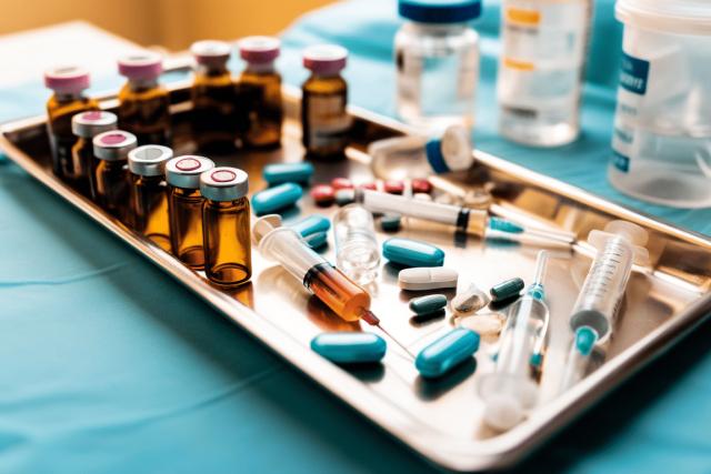 A close-up of a medication tray in an emergency room, with syringes, vials, and pill bottles neatly arranged, but one item slightly out of place to subtly suggest the potential for errors in a high-pressure environment.