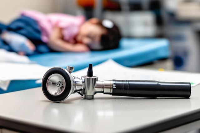 A close-up of a pediatric otoscope, used for examining ears, resting on a sterile hospital tray