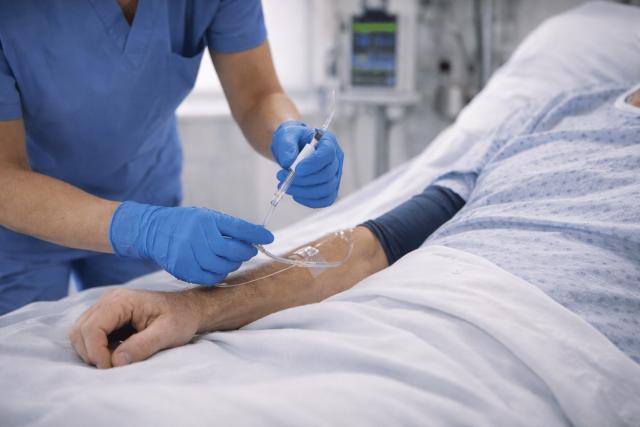 Nurse adjusting an IV drip on a patient’s arm in a hospital